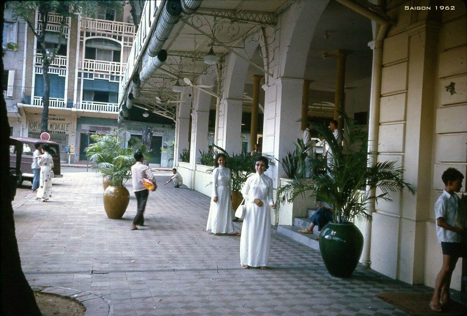  Hai phụ nữ mặc áo dài đứng trước khách sạn Continental